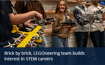 A group of students hold LEGO models of planes in a lab setting